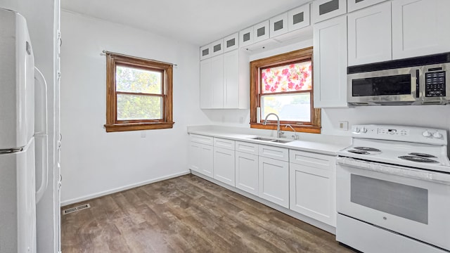 kitchen with dark hardwood / wood-style flooring, white appliances, sink, and white cabinets