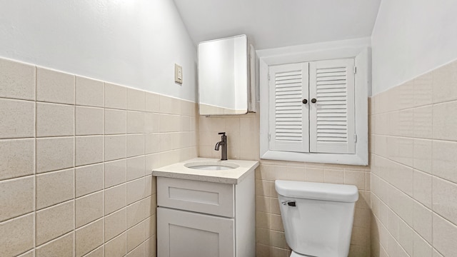 bathroom with vanity, toilet, and tile walls