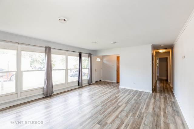 spare room with light wood-type flooring, a wealth of natural light, and crown molding