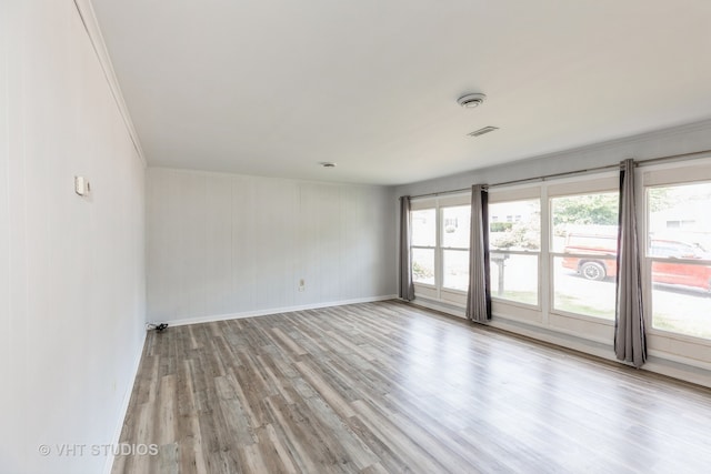 spare room with a wealth of natural light, light hardwood / wood-style flooring, and crown molding