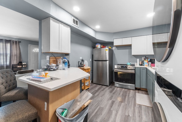 kitchen with gray cabinetry, white cabinetry, appliances with stainless steel finishes, and light wood-type flooring