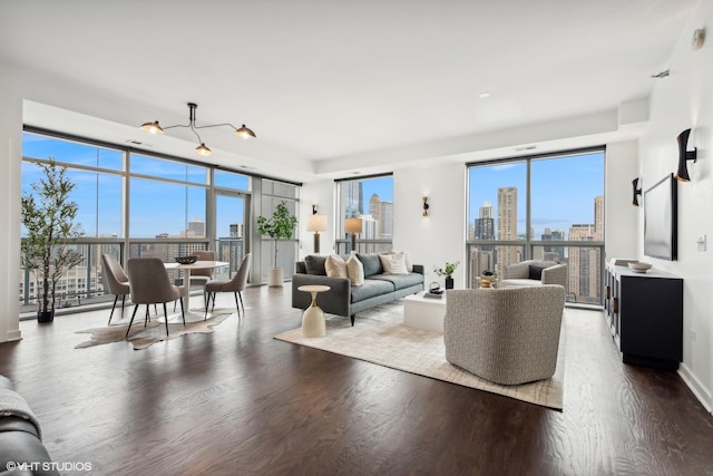 living room featuring a wealth of natural light, wood-type flooring, and a notable chandelier