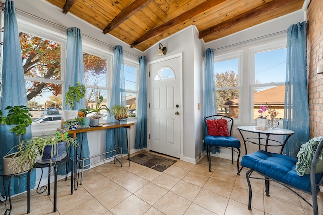 foyer entrance with vaulted ceiling with beams, light tile patterned flooring, wooden ceiling, and brick wall