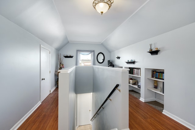 hallway with hardwood / wood-style floors, built in shelves, and lofted ceiling