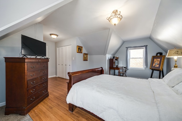 bedroom with light hardwood / wood-style floors, lofted ceiling, and a closet