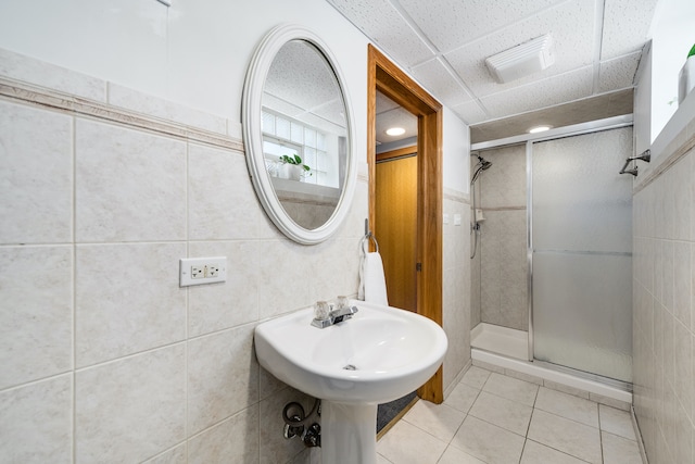 bathroom featuring tile patterned flooring, a shower with shower door, and tile walls