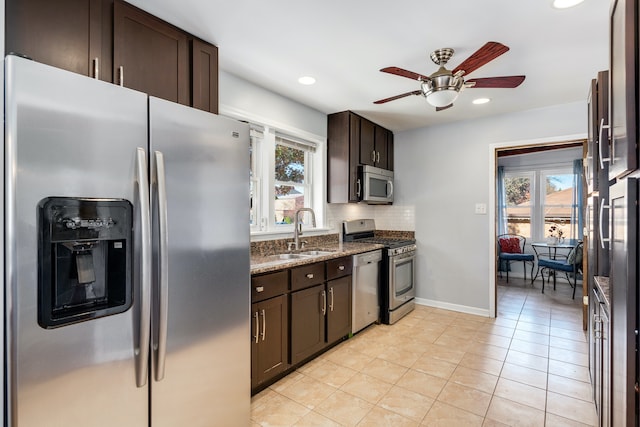 kitchen featuring ceiling fan, sink, tasteful backsplash, dark stone counters, and appliances with stainless steel finishes