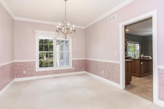 carpeted spare room with a chandelier, a healthy amount of sunlight, and ornamental molding