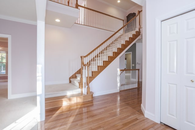 staircase with hardwood / wood-style flooring and crown molding