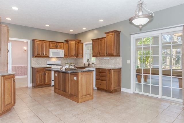 kitchen with dark stone counters, white appliances, a kitchen island, and light tile patterned flooring