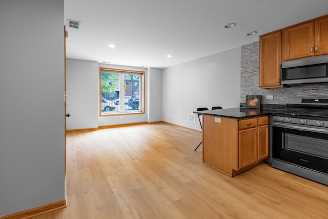 kitchen featuring decorative backsplash, kitchen peninsula, appliances with stainless steel finishes, and light hardwood / wood-style flooring