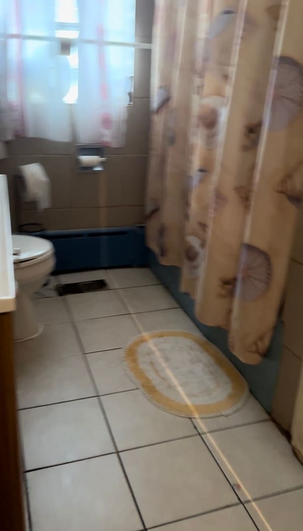 bathroom featuring tile patterned floors, toilet, and shower / bathtub combination with curtain