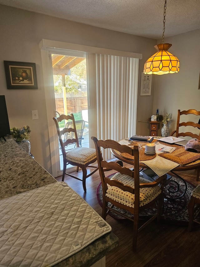 dining space with wood-type flooring and a textured ceiling