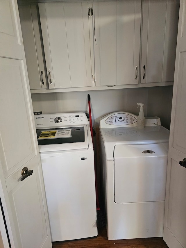 laundry room with dark hardwood / wood-style flooring, washing machine and dryer, and cabinets