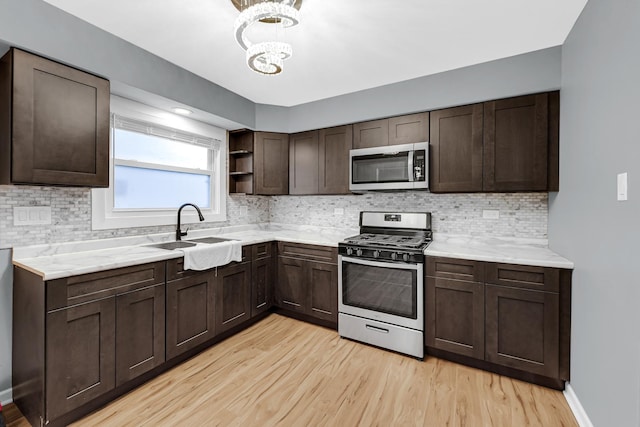 kitchen with open shelves, dark brown cabinetry, stainless steel appliances, and a sink