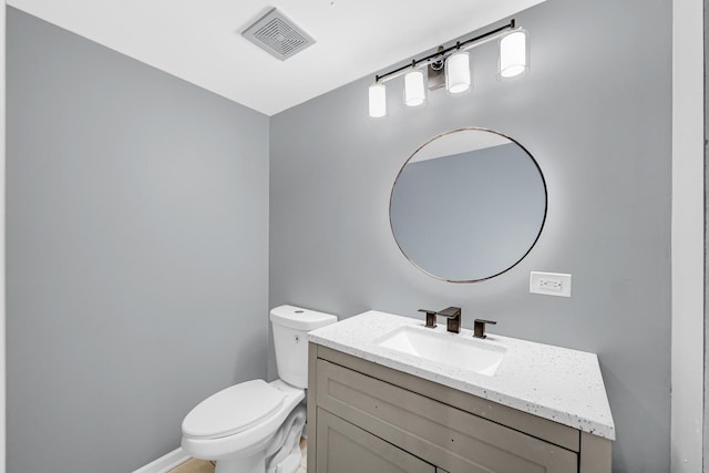 half bath featuring toilet, vanity, baseboards, and visible vents