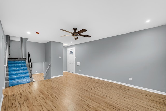 unfurnished living room featuring light wood finished floors, recessed lighting, ceiling fan, baseboards, and stairs