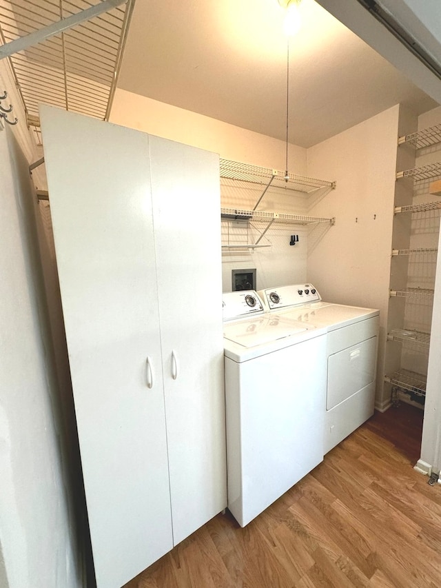 clothes washing area with hardwood / wood-style floors and washing machine and clothes dryer