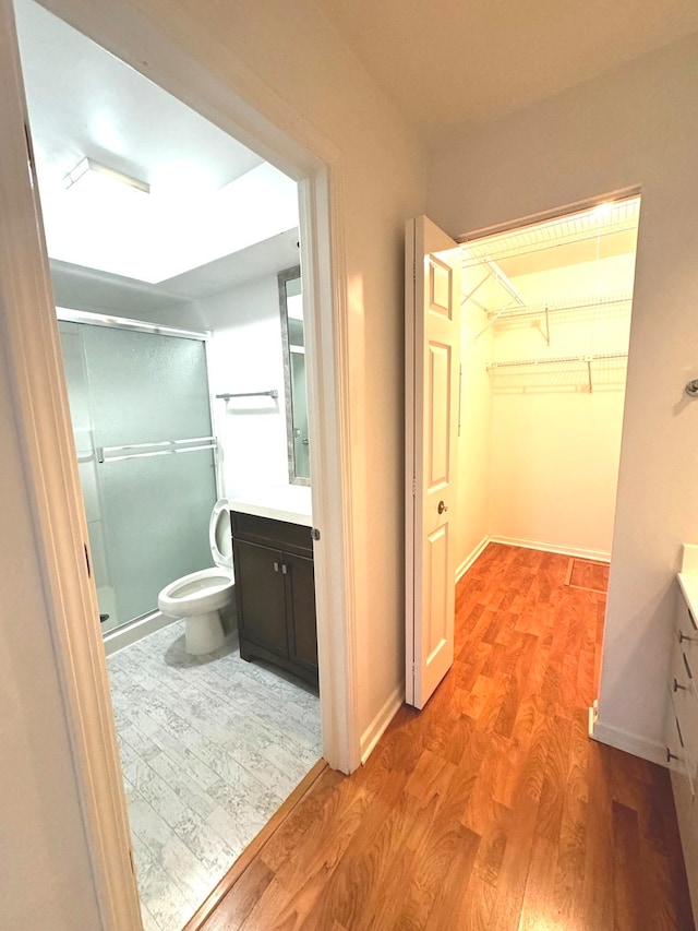 bathroom with toilet, a shower with door, vanity, and hardwood / wood-style flooring