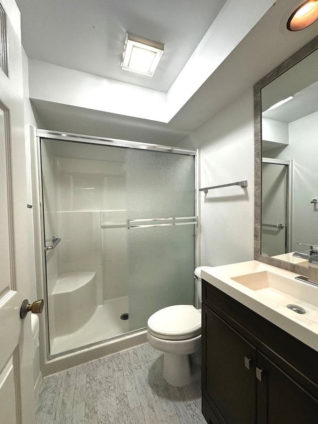 bathroom featuring hardwood / wood-style flooring, toilet, and a shower with shower door