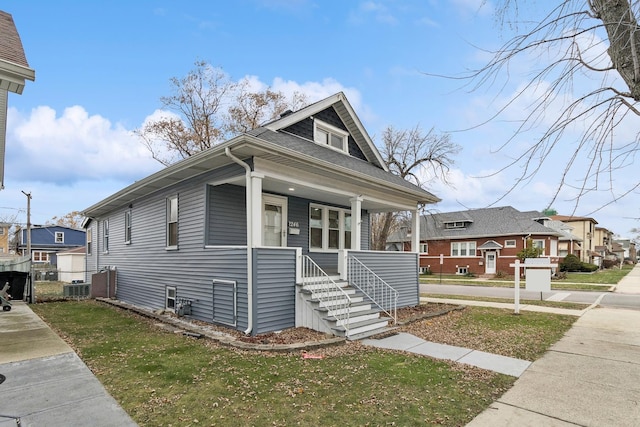 bungalow-style house with a porch, central air condition unit, and a front lawn