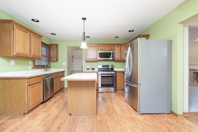 kitchen with stainless steel appliances, hanging light fixtures, light hardwood / wood-style flooring, and a center island