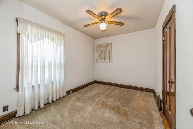 empty room with carpet flooring, ceiling fan, and a textured ceiling