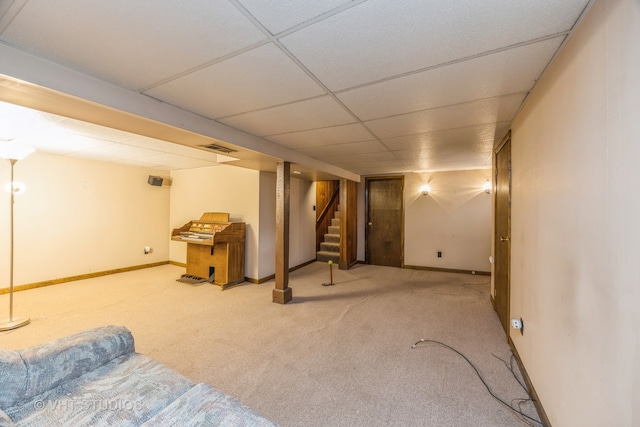 basement with a drop ceiling and light colored carpet