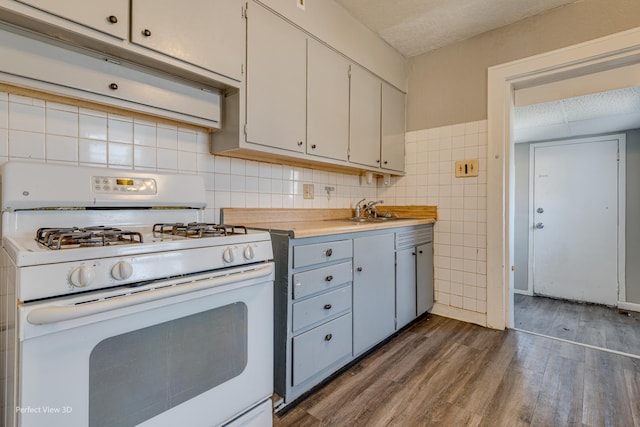 kitchen with sink, dark hardwood / wood-style flooring, a textured ceiling, white cabinets, and white gas range oven