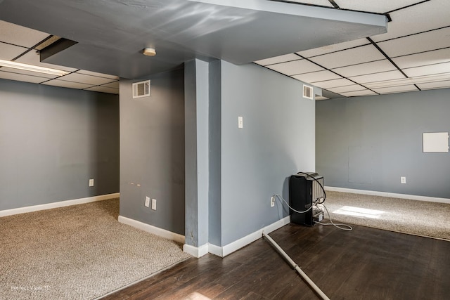 basement with a paneled ceiling and dark wood-type flooring