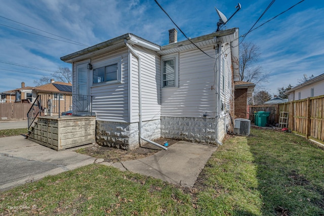 exterior space with central air condition unit and a yard