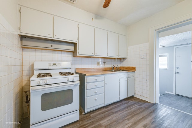 kitchen featuring hardwood / wood-style floors, white cabinets, sink, tile walls, and white range with gas stovetop