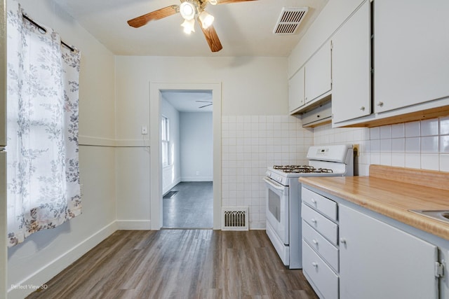 kitchen with ceiling fan, light hardwood / wood-style floors, white range with gas cooktop, white cabinets, and tile walls