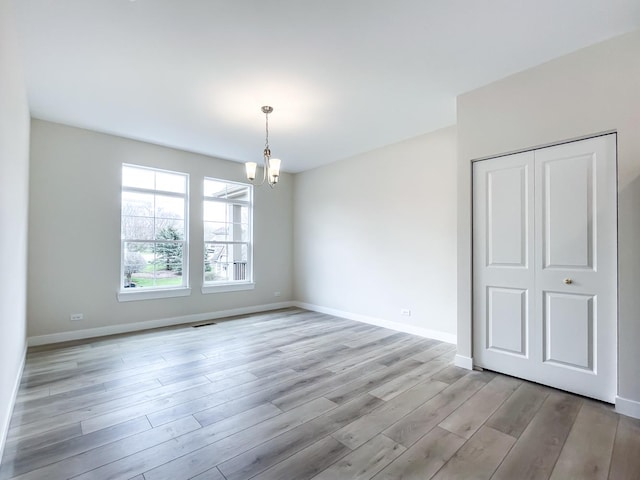 235 Regency Ct Unit B, Wauconda, IL 60084 - unfurnished room with a chandelier, light wood-style flooring, and baseboards