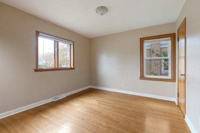 spare room with plenty of natural light and light hardwood / wood-style flooring