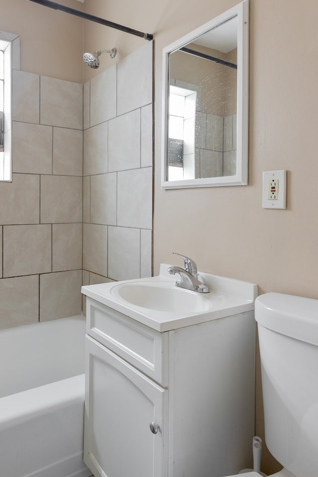 full bathroom featuring vanity, tiled shower / bath combo, and toilet