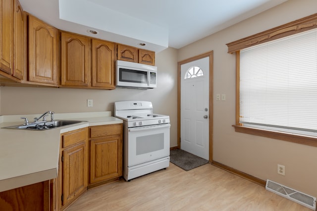 kitchen featuring white appliances, sink, and light hardwood / wood-style flooring