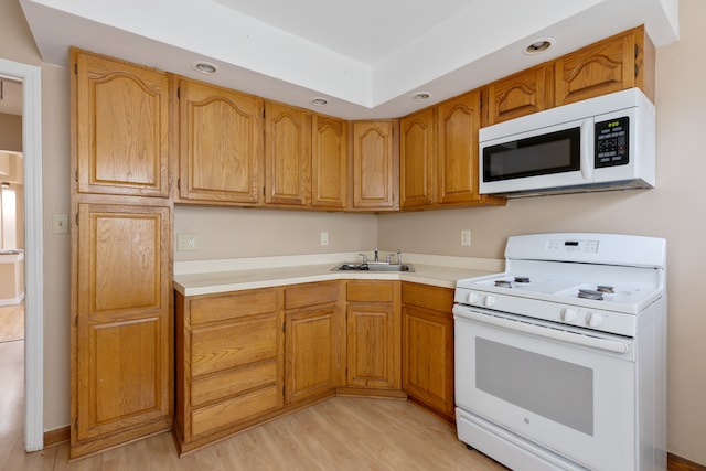 kitchen with white appliances, sink, and light hardwood / wood-style floors