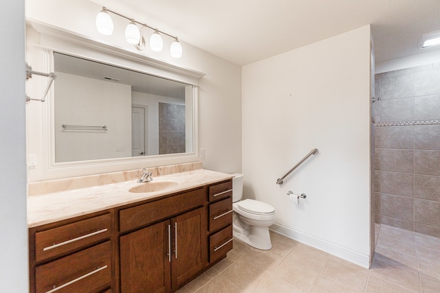 bathroom featuring toilet, vanity, tile patterned floors, and tiled shower