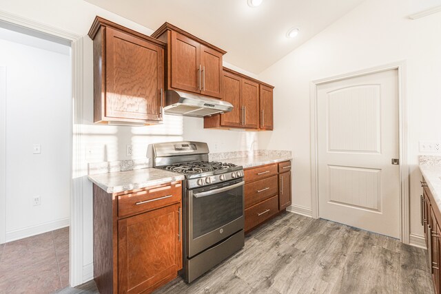 kitchen with light hardwood / wood-style floors, gas range, vaulted ceiling, and light stone countertops