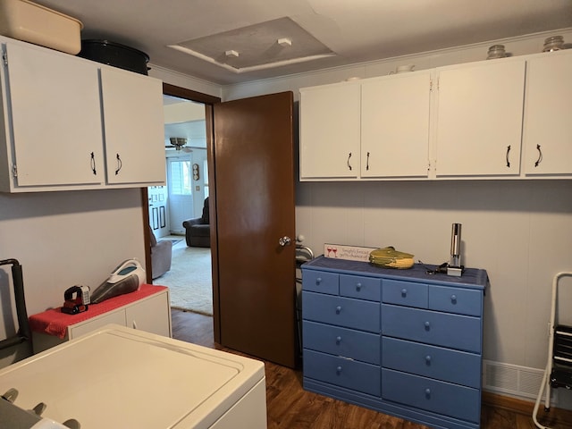 clothes washing area with washer / clothes dryer, dark wood-type flooring, and cabinets