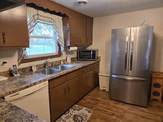 kitchen featuring sink, dark hardwood / wood-style floors, stainless steel fridge, dishwasher, and backsplash