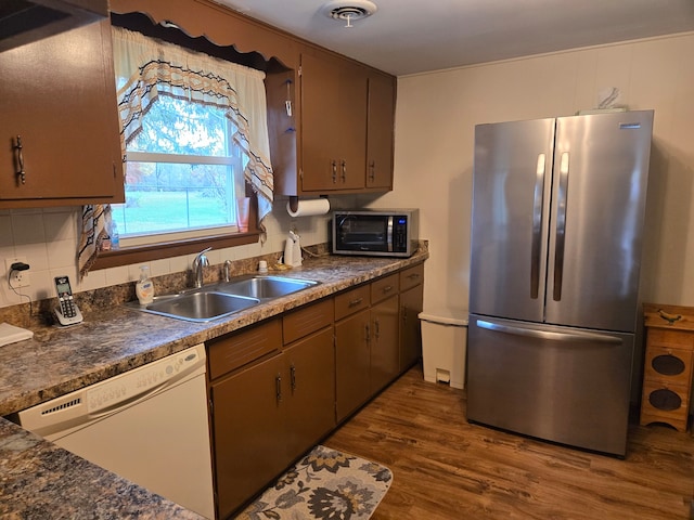 kitchen with sink, stainless steel refrigerator, dark hardwood / wood-style floors, dishwasher, and backsplash