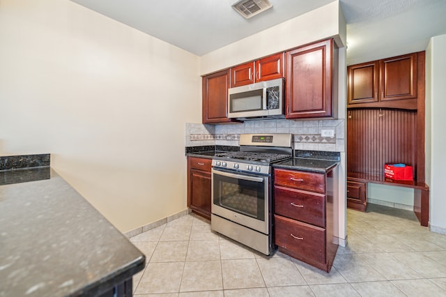 kitchen with stainless steel appliances, dark stone counters, light tile patterned floors, and tasteful backsplash