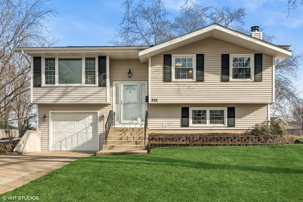 raised ranch featuring a front yard and a garage