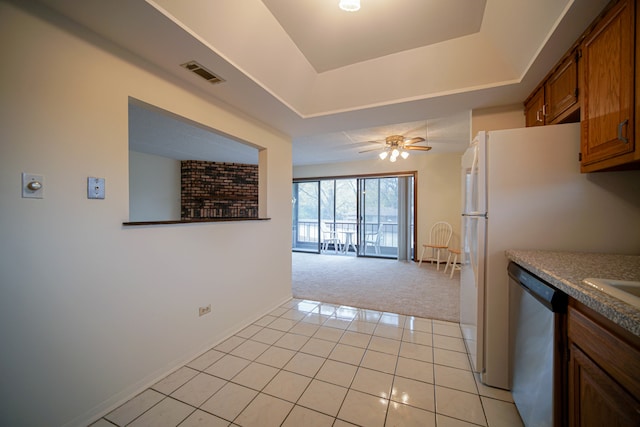 kitchen with a tray ceiling, ceiling fan, stainless steel dishwasher, and light carpet