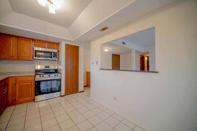 kitchen featuring a raised ceiling, light tile patterned floors, and stainless steel appliances