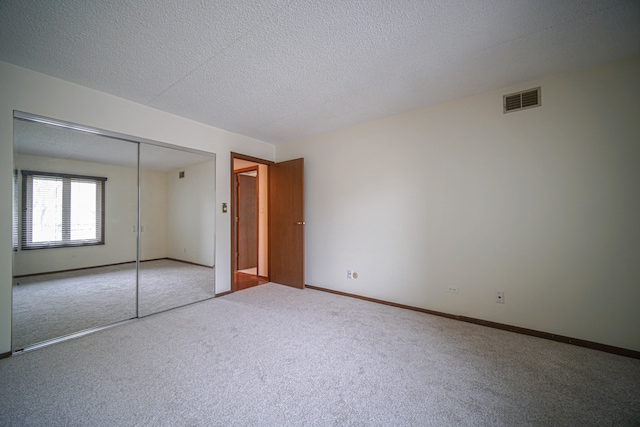 unfurnished bedroom featuring a textured ceiling, carpet floors, and a closet