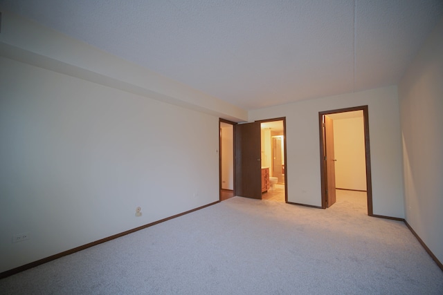 unfurnished bedroom featuring ensuite bathroom and light carpet