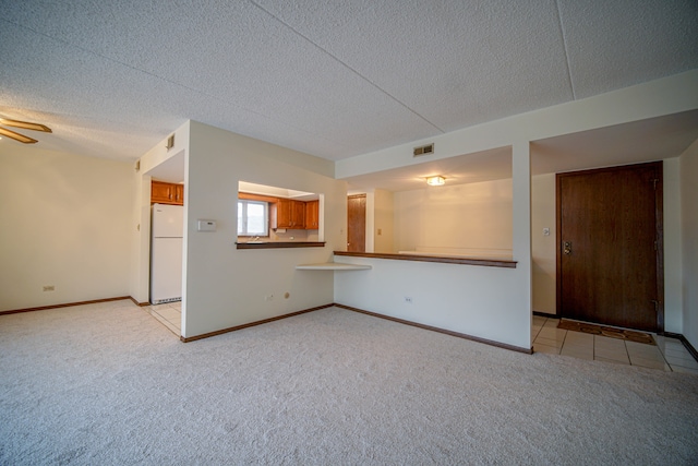 unfurnished living room featuring light carpet, ceiling fan, and a textured ceiling